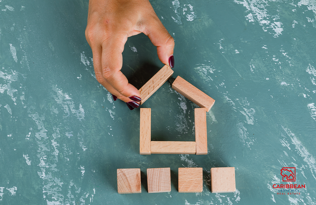 Hand assembling a small wooden house model, representing the concept of home construction in a creative and playful manner.